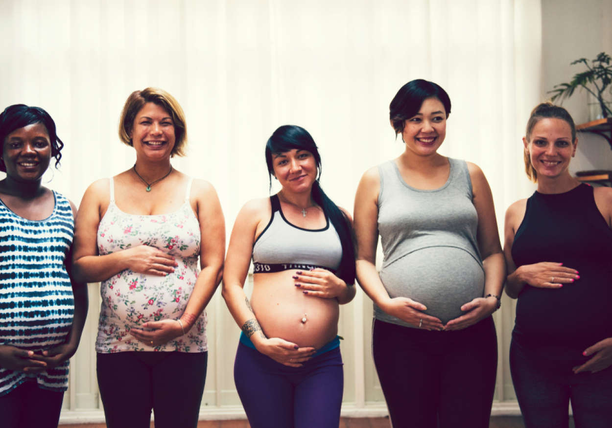 Pregnant women of standing next to each other holding their belly