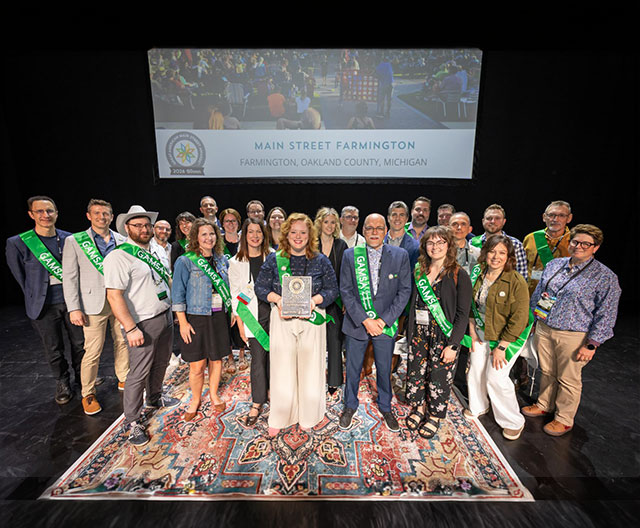 Tom Gilbert/Rogue Monkey Media for the 2026 Main Street Now Conference Group of people wearing sashes on a stage.