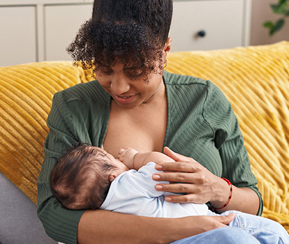 Mother breast feeding her baby on the couch at home.